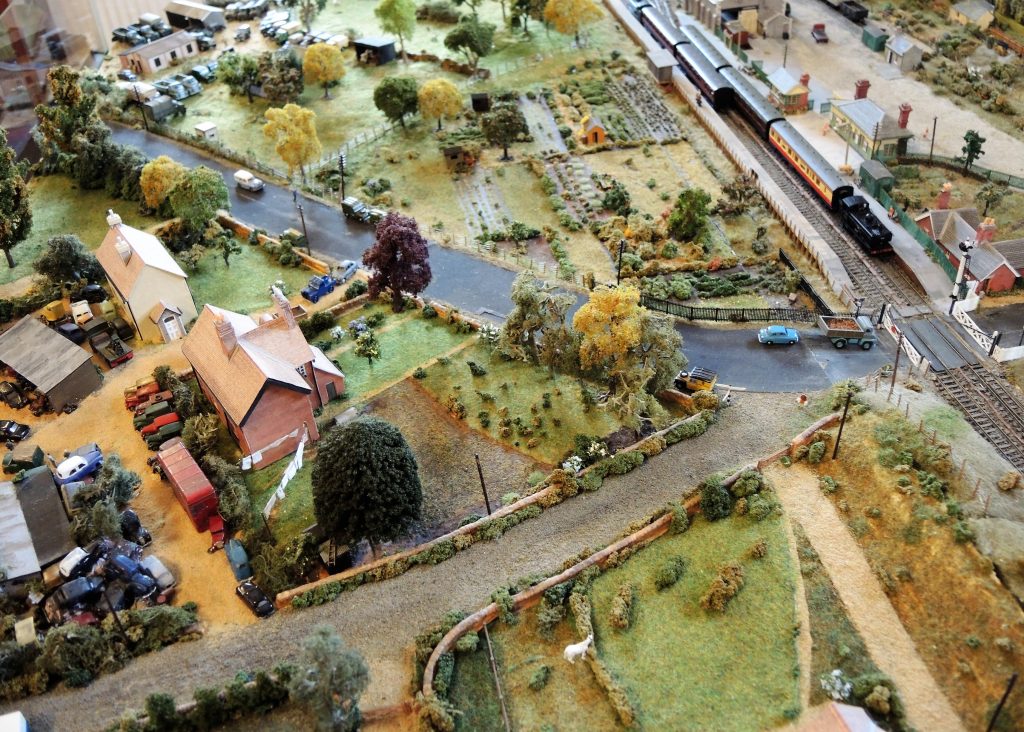 Model of Eynsham Station in the 1950s, created by David Thomas. View from above of the area around the station, with houses, allotments, fields and trees. Two trains sit at the station.