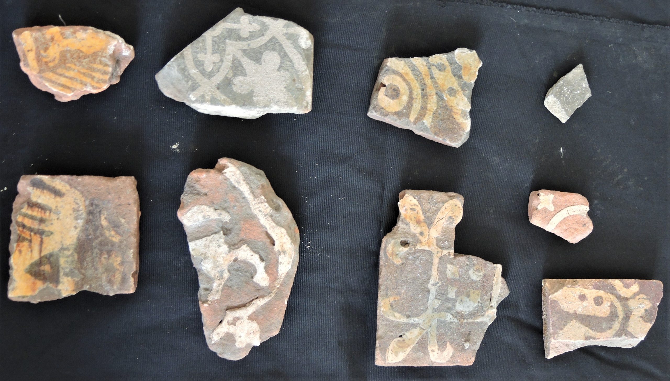 Nine small fragments of floor tiles from Eynsham Abbey, dating from the 13th to the 15th century CE.