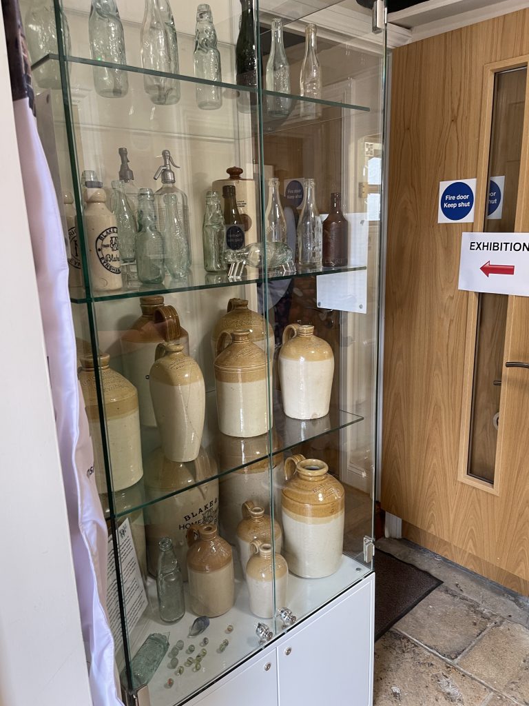 Display cabinet with ceramic and glass bottles make by Blakes & Co, an Eynsham company founded in the 19th century.