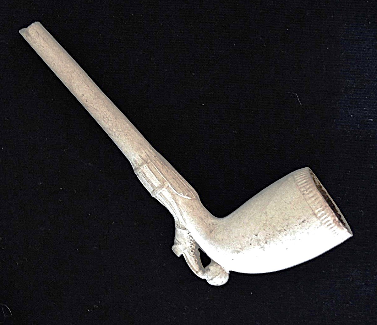 A 19th century clay pipe, which has a raised image of a ladies shoe kicking a ball.