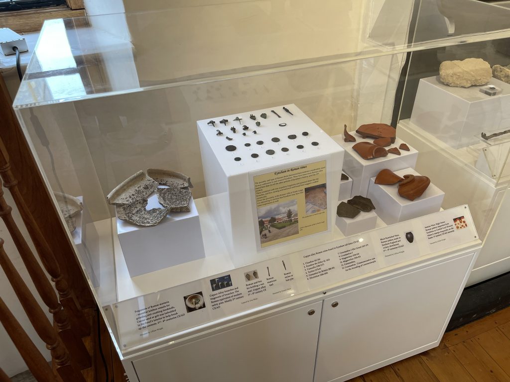 A display case with a selection of Roman pottery, coins and brooches
