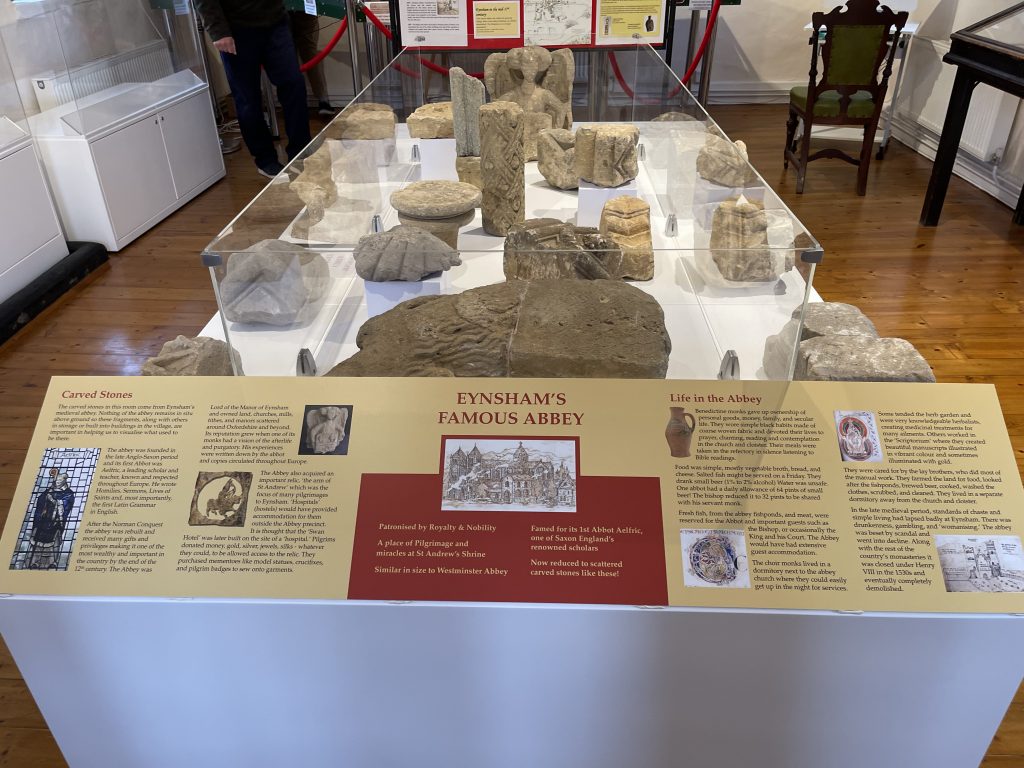 Cabinet display of stones from Eynsham Abbey with a panel describing carved stones and life in the Abbey.